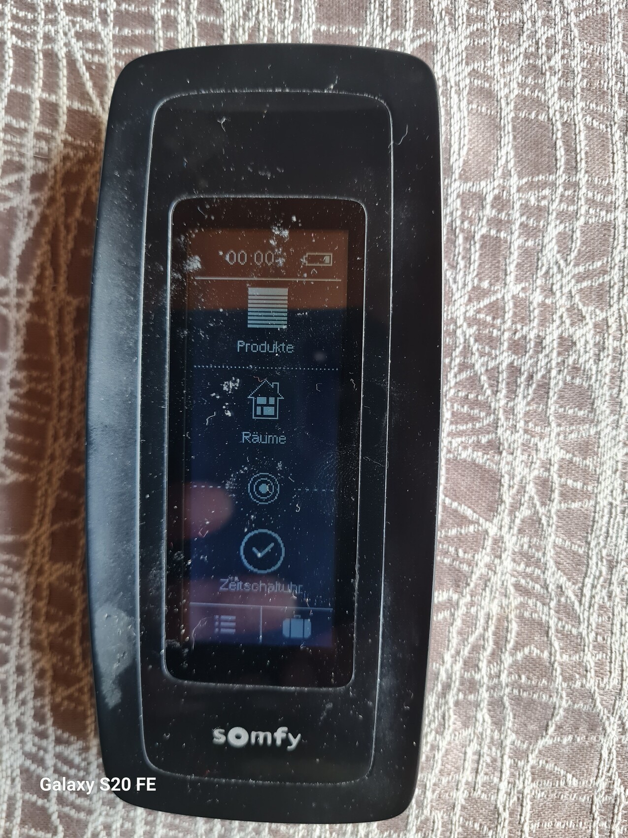 Kleines schwarzes Somfy-Displaygerät mit Touchscreen, zeigt Symbole für Produkte, Räume und Timer.