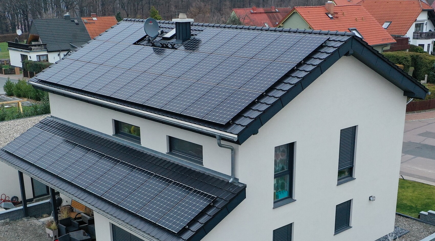 Modernes Wohnhaus mit großer Solarstromanlage auf zwei Dachflächen, umliegende Häuser