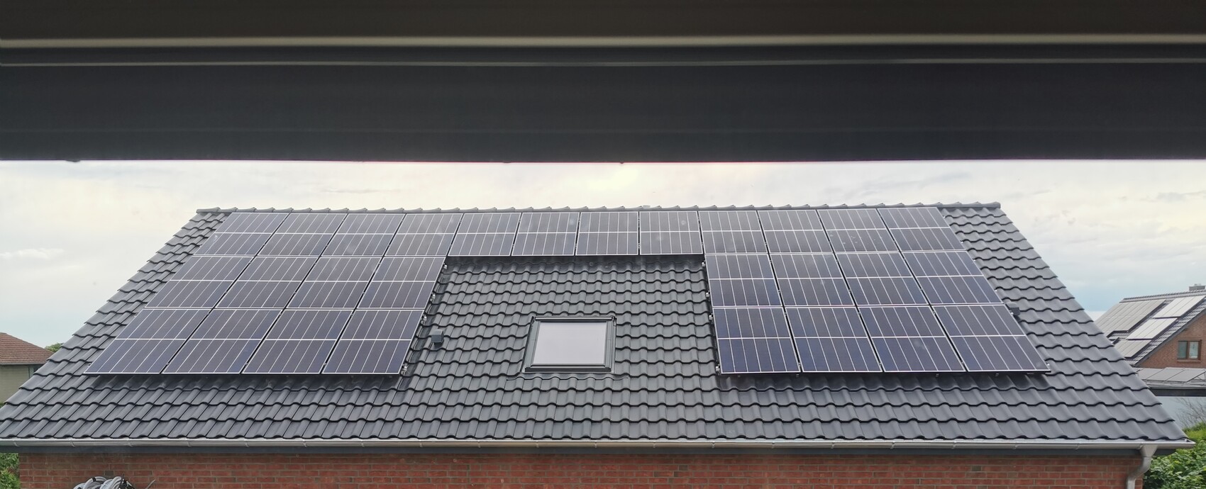 Dach eines Hauses mit Photovoltaik-Solaranlage auf grauem Ziegeldach
