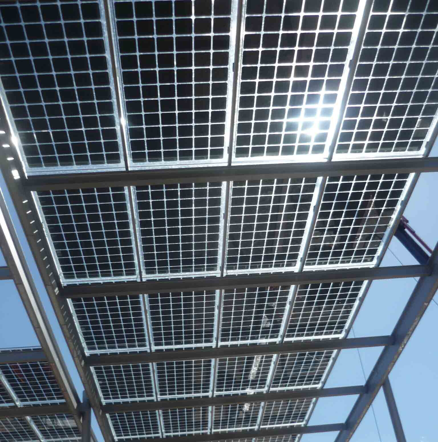 Außenansicht von Solarpanelen auf Stahlkonstruktion gegen blauen Himmel.