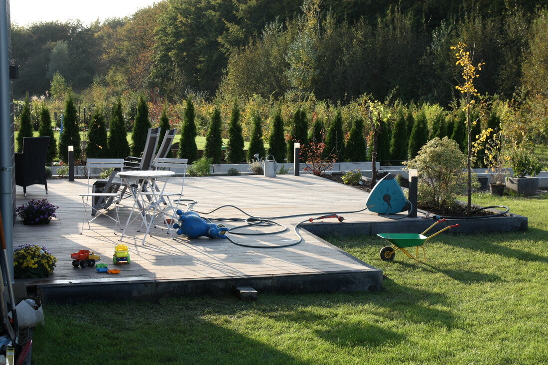 sonnige-terasse-im-garten-mit-pflanzen-holzdeck-und-spielzeug.jpg