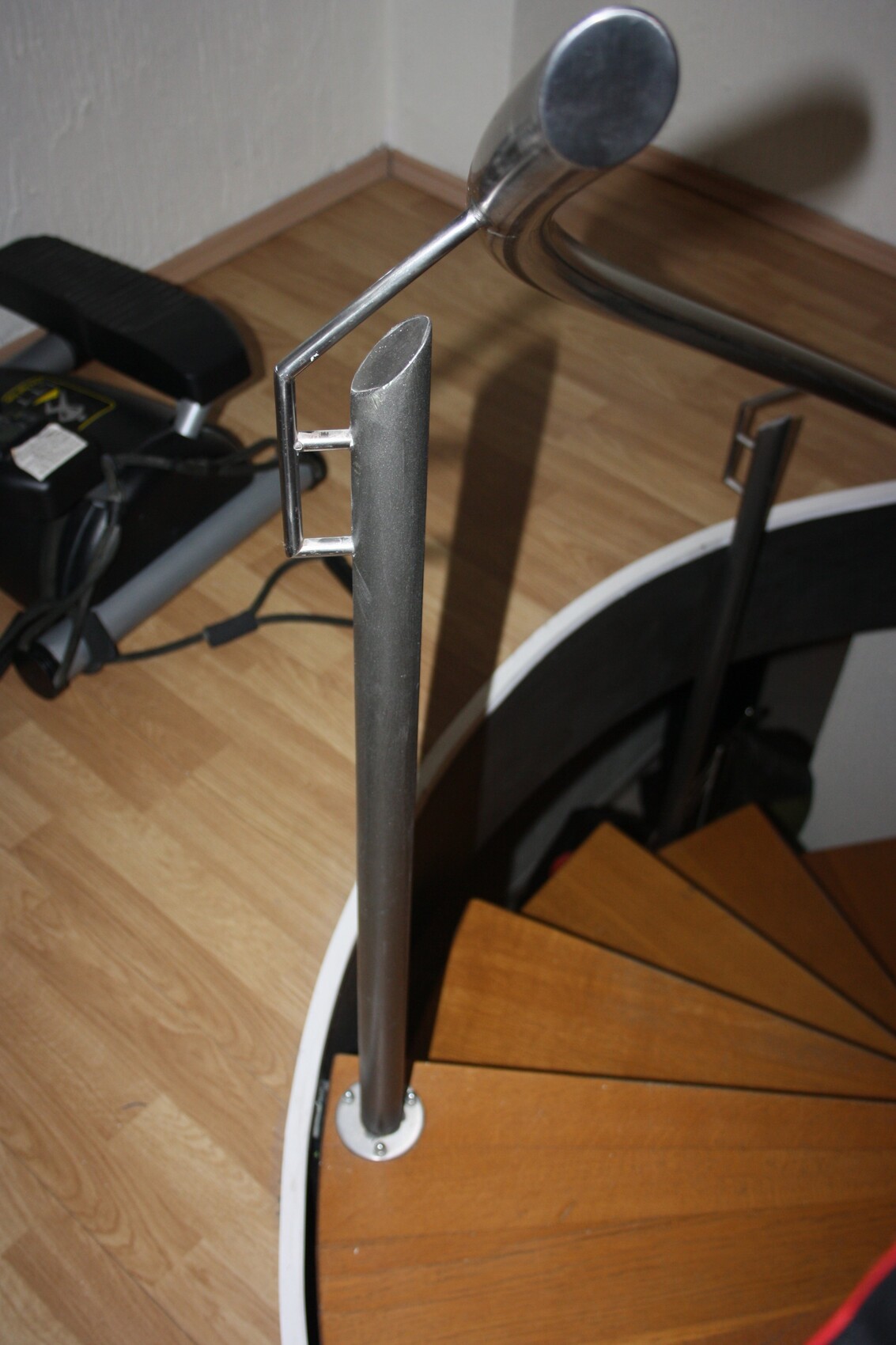 Innenaufnahme einer Spiraltreppe mit Metallhandlauf und Holztreppenstufen.