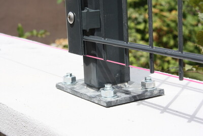 Metall-Basisplatte mit Schraubbolzen befestigt Zaunpfosten auf Beton.