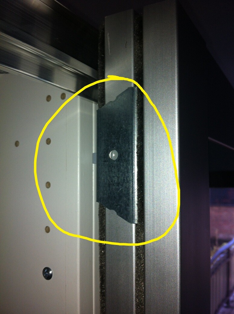 Nahaufnahme einer metallischen Scharnierplatte am Türrahmen mit Schraubenloch.
