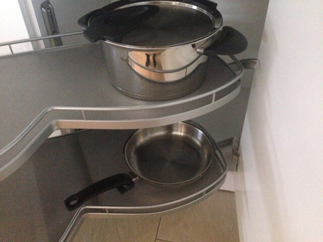 Ausziehbarer Küchenschrank mit Metallpfannen und einem Topf auf den Ablagen