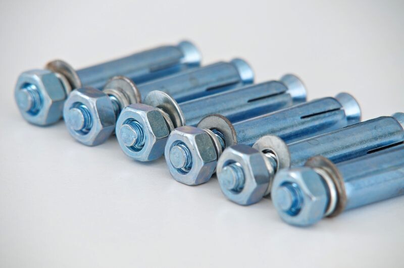 Mehrere Metallbolzen mit Unterlegscheiben und Muttern in Reihe