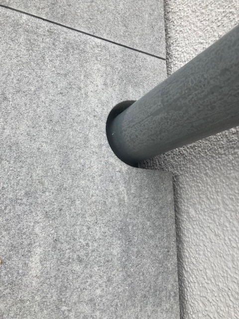 Stahlrohr führt durch eine runde Öffnung in eine graue Betonwand.