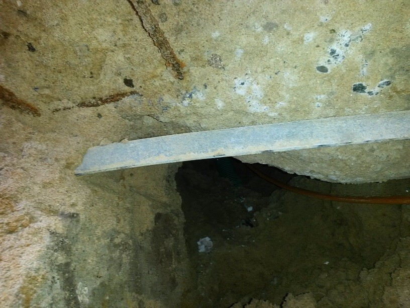 Baugrube im Rohbaufundament mit Beton, Erde und Rohren sichtbar