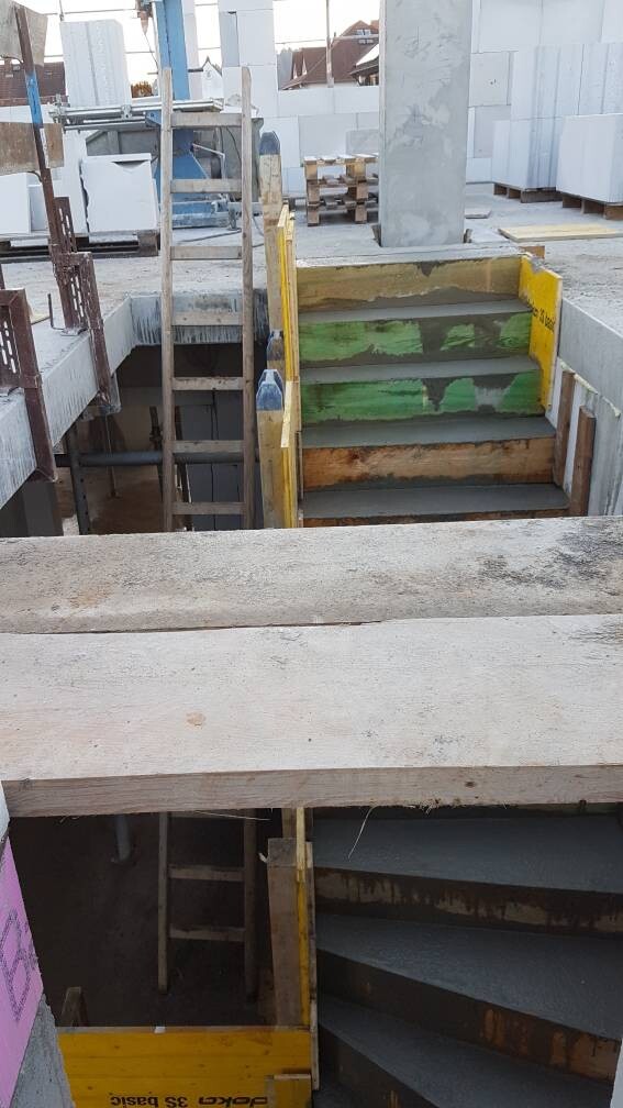 Baustellen-Stufen aus Holz mit gelbem Geländer, grün gestrichene Stufen in Baugrube.