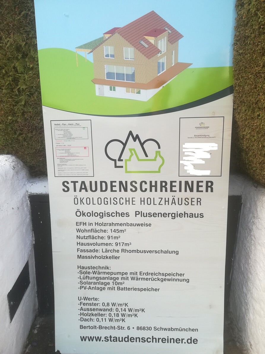 Außenposter mit 3D-Holzhausmodell und Staudenschreiner-Informationsplakat