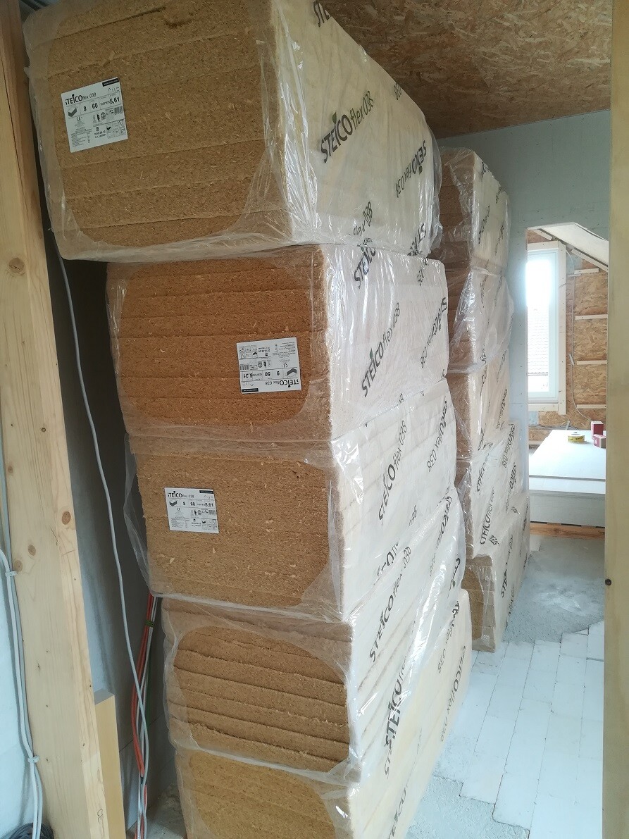 Mehrere Holzfaser-Dämmplatten (Steico) in Plastik verpackt, gestapelt im Baubereich.