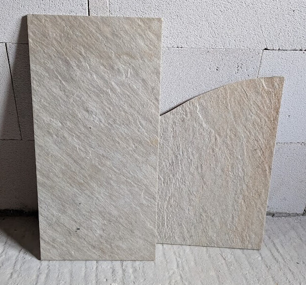 Zwei große Steinplatten lehnen an einer Betonwand im Baubereich.