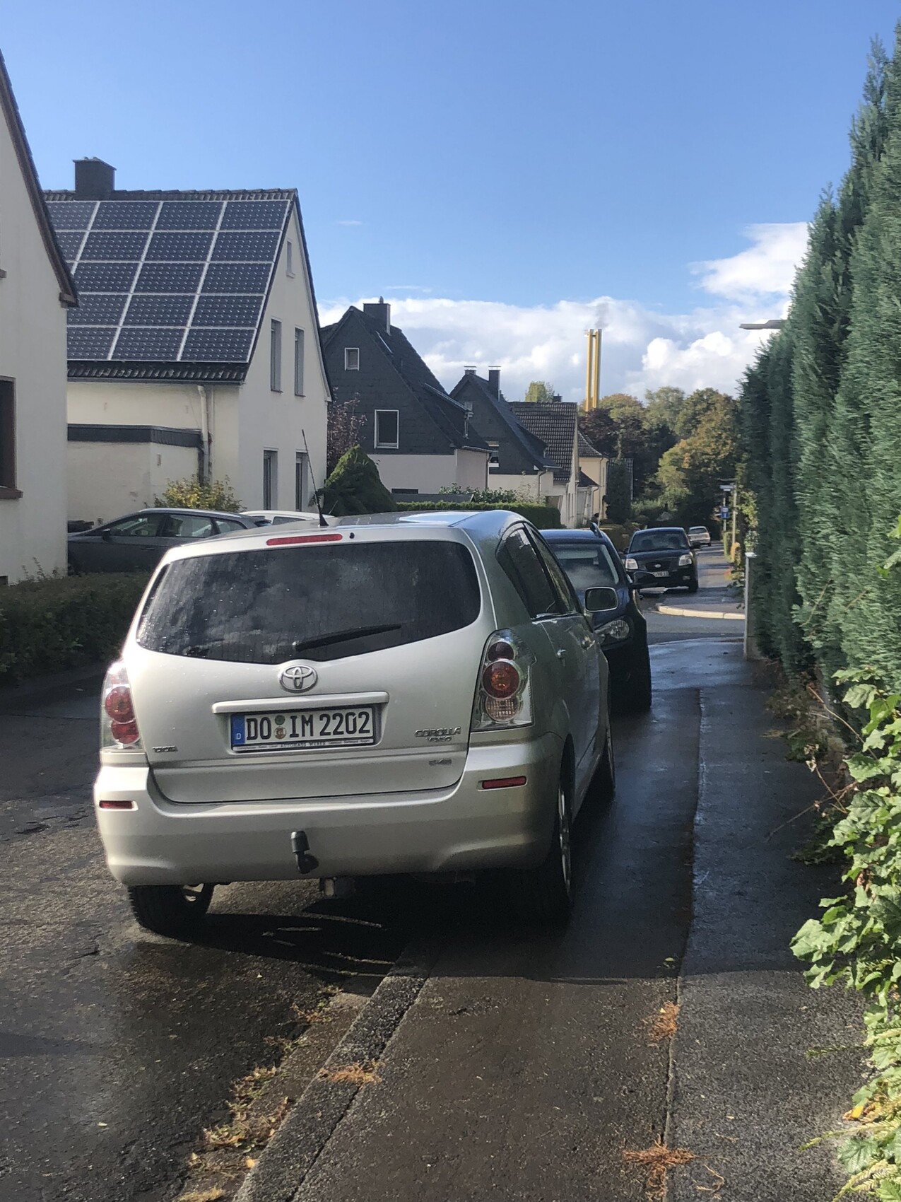 Auto geparkt in einer Wohnstraße vor Häusern mit Solarpanelen auf dem Dach