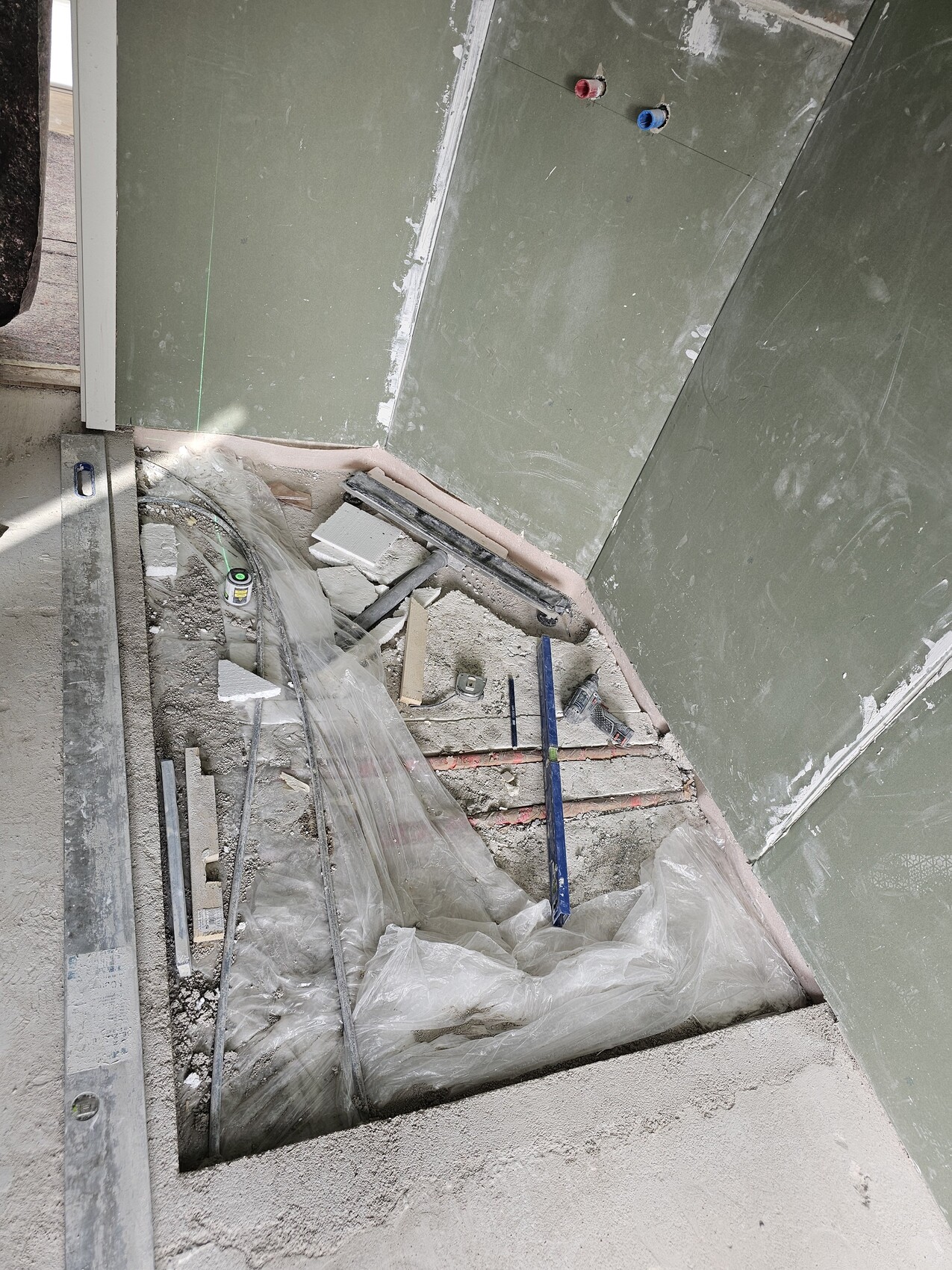 Baustellenaufnahme: offener Stufenabgang im Rohbau mit Plastikfolie, Bauabfall und Rohren.