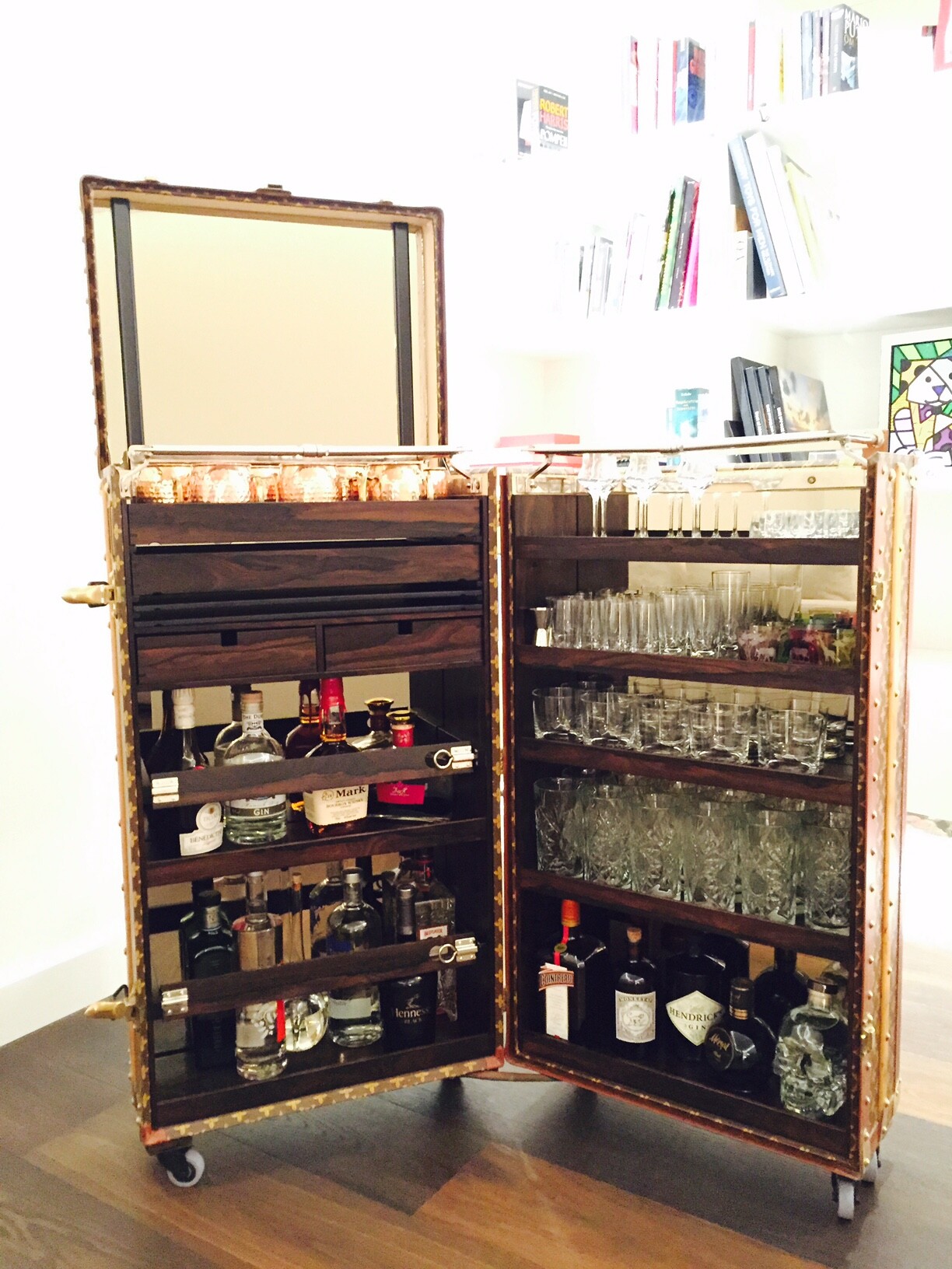 Offene Vintage-Bar auf Koffern mit Flaschen, Gläsern und Regalen, auf Rollen.
