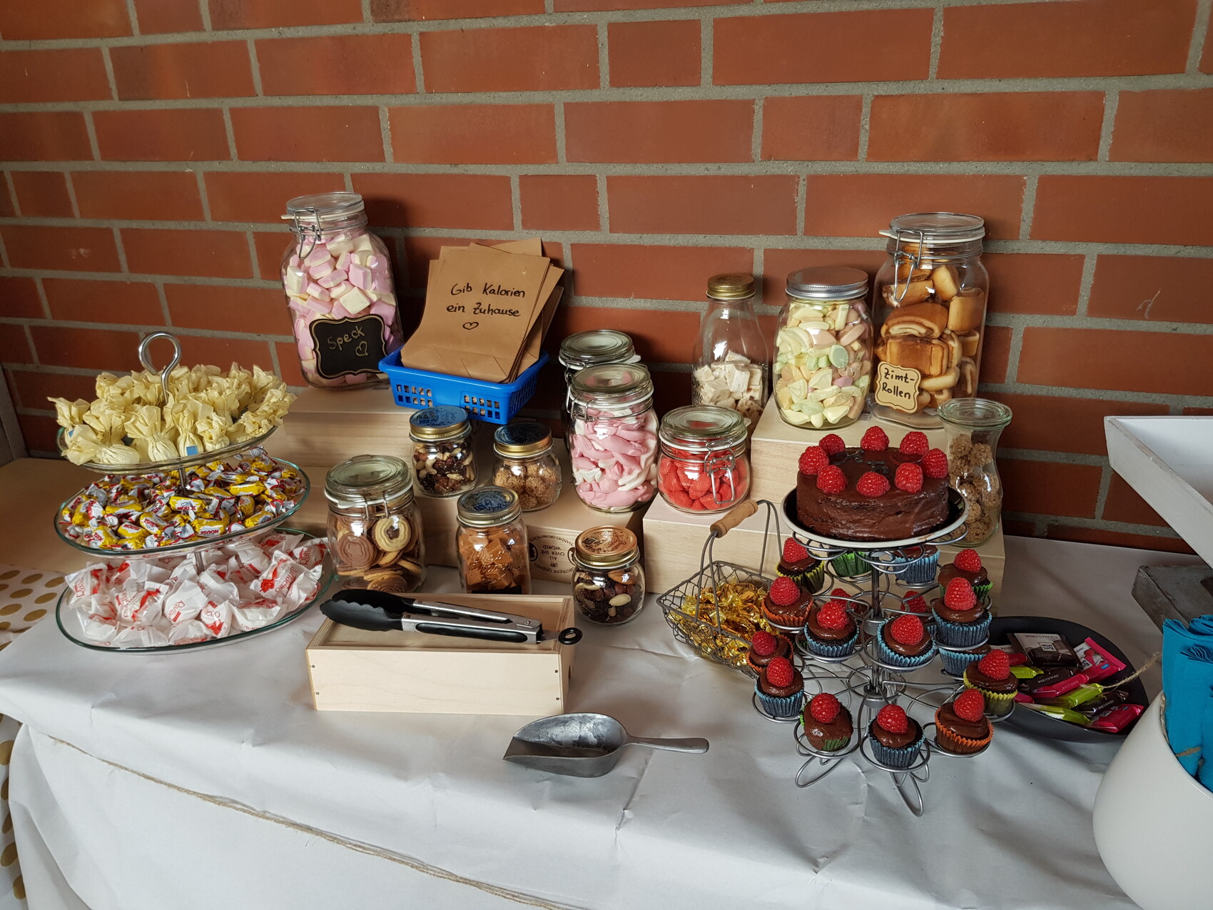 Süßigkeitenbuffet auf Tisch: Gläser mit Marshmallows, Keksen, Kuchen, Cupcakes, Himbeer-Torte.