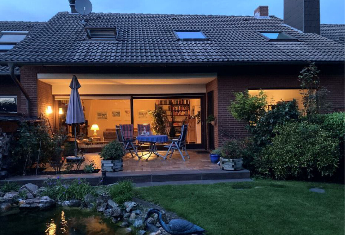 Abendstimmung auf Terrasse mit Garten, Sitzgruppe, Teich im Vorgarten eines Hauses