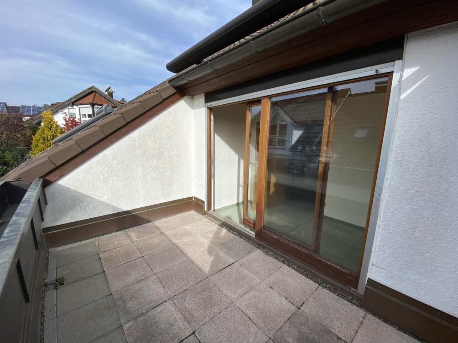 Balkon mit bodentiefen Glastüren am Haus, Terrassenplatten und Dachüberbau