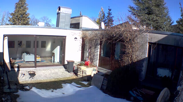 Außenansicht eines Wohnhauses mit Terrasse, Garten und Bauholz im Winter