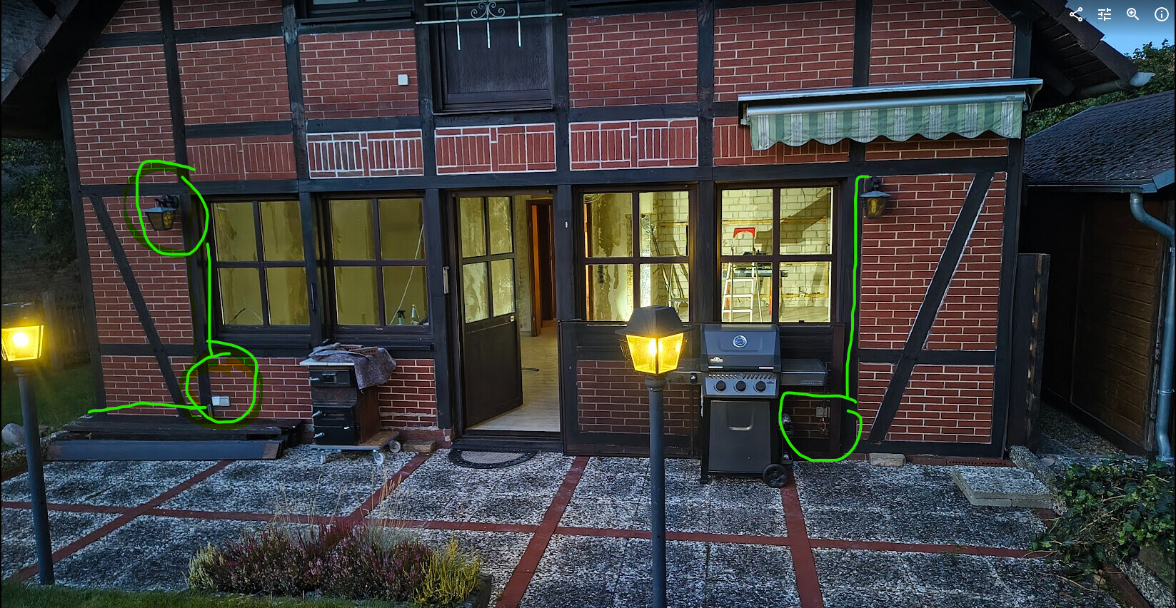 Außenansicht eines Fachwerkhauses mit Backsteinwänden, Terrasse, Gartenlampen und Grill