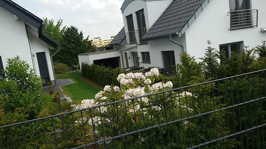 Weiße moderne Wohnhäuser mit Garten, Zaun, Balkon und gepflegten Grünflächen