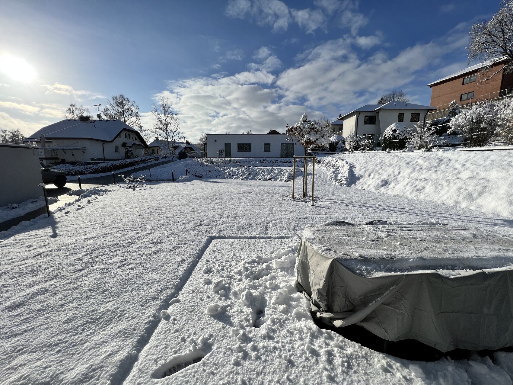 Verschneiter Gartenhof mit Wohnhäusern, Schnee bedeckt, blauer Himmel