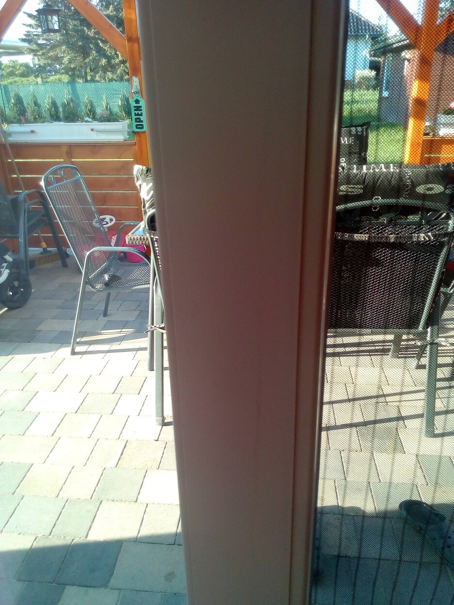 Terrasse mit Metallstuehlen, Grill und Steinpflaster im Gartenbereich