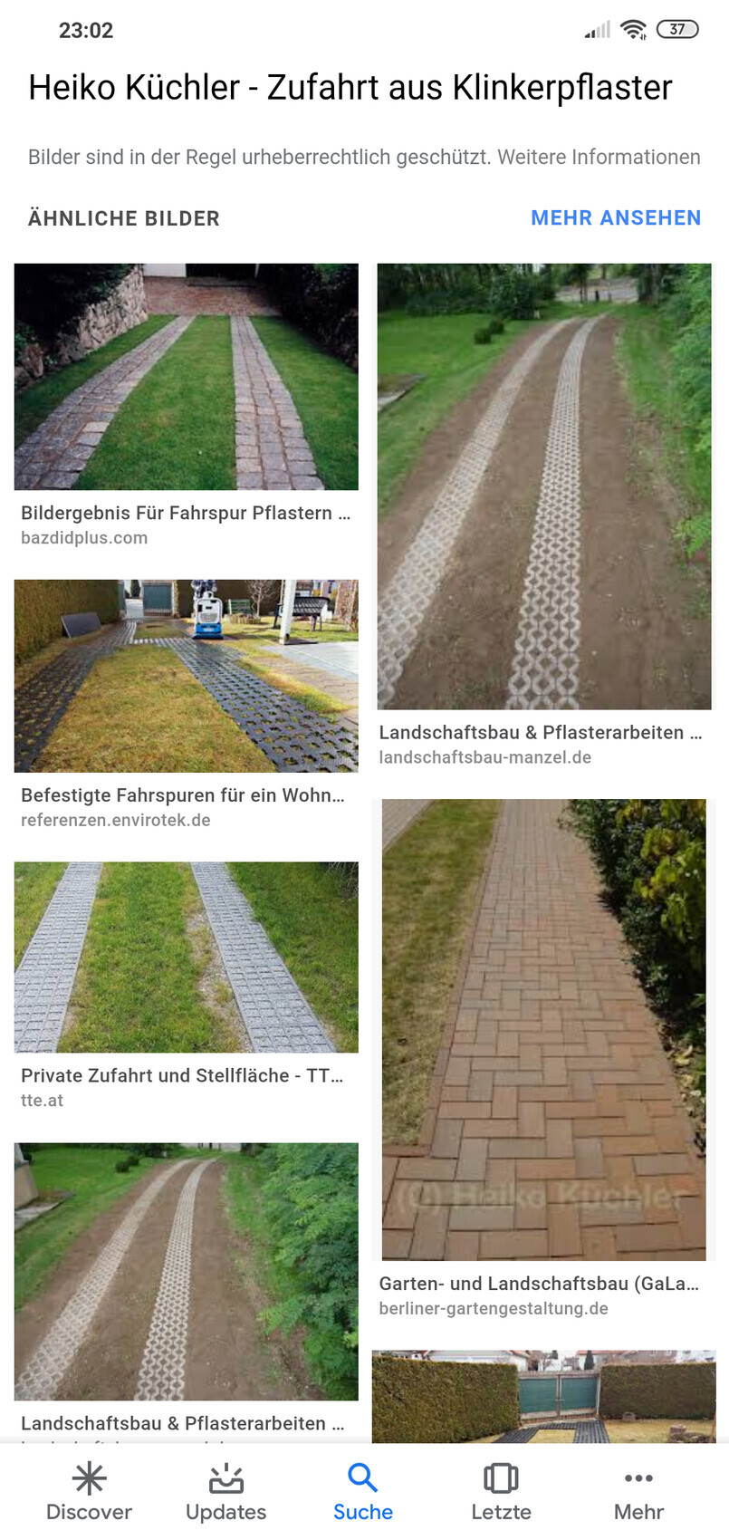 Gepflasterter Gartenweg mit zwei parallelen Pflasterstreifen neben Gras.