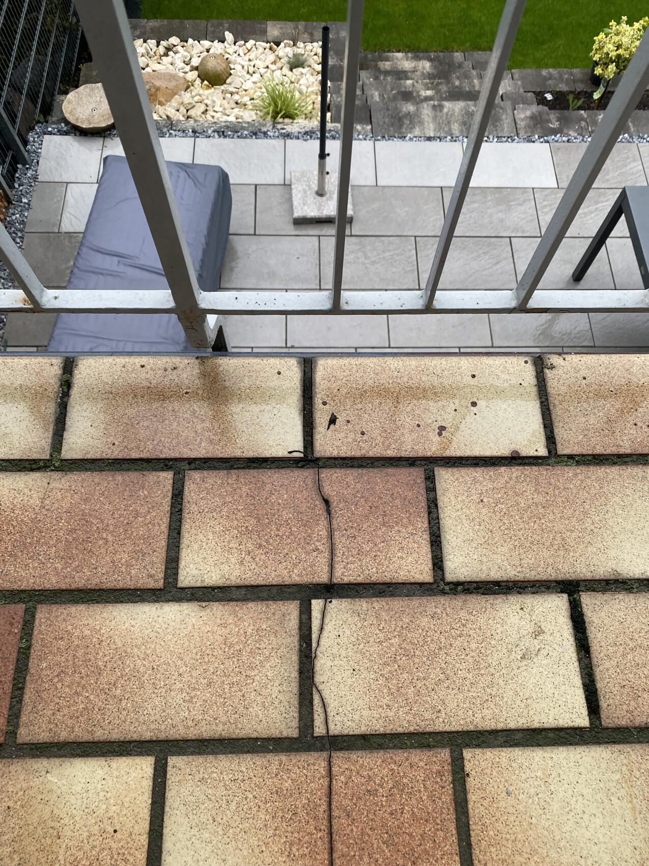 Außenbereich mit terrassenplatten, Geländer, Blick auf darunter liegende Fläche.
