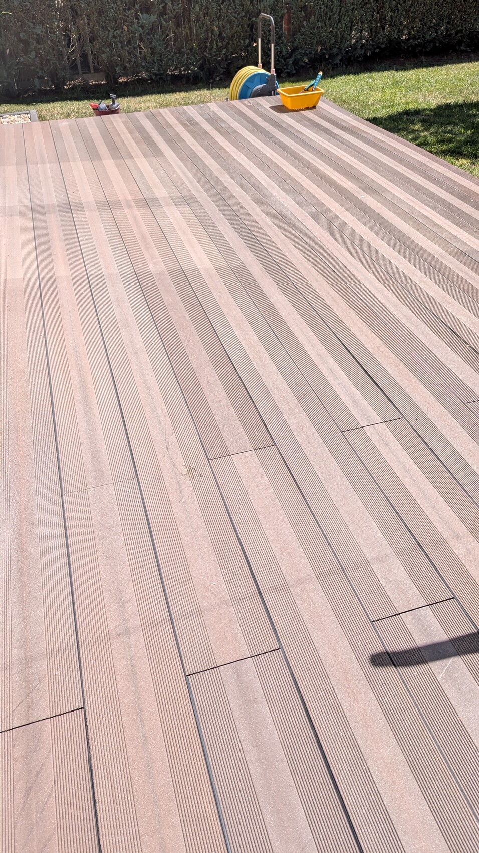 Holzdeck mit langen braunen Planken; im Hintergrund Schlauchaufroller und gelbe Kiste.