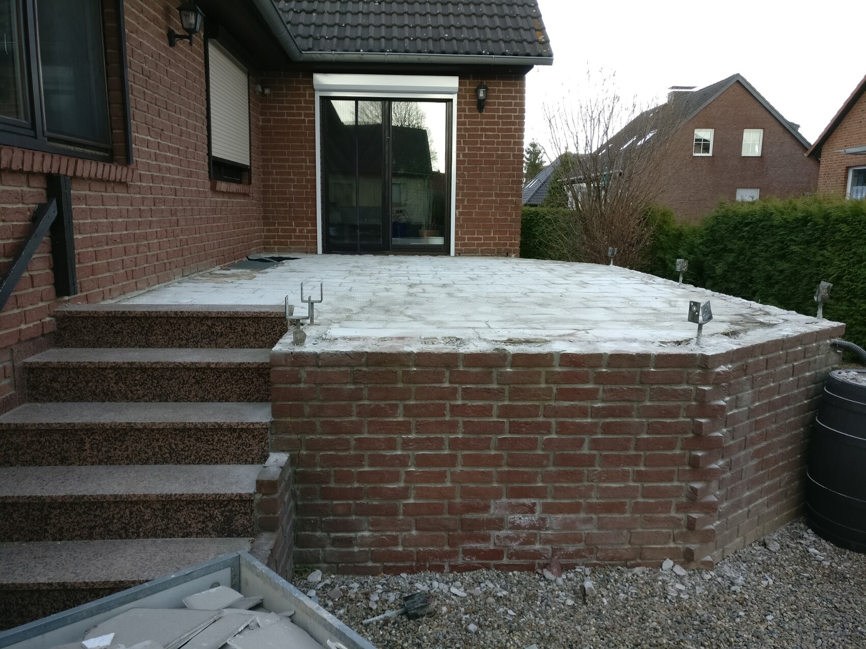 Terrasse aus Backstein mit Stufen und Betonboden hinter dem Haus