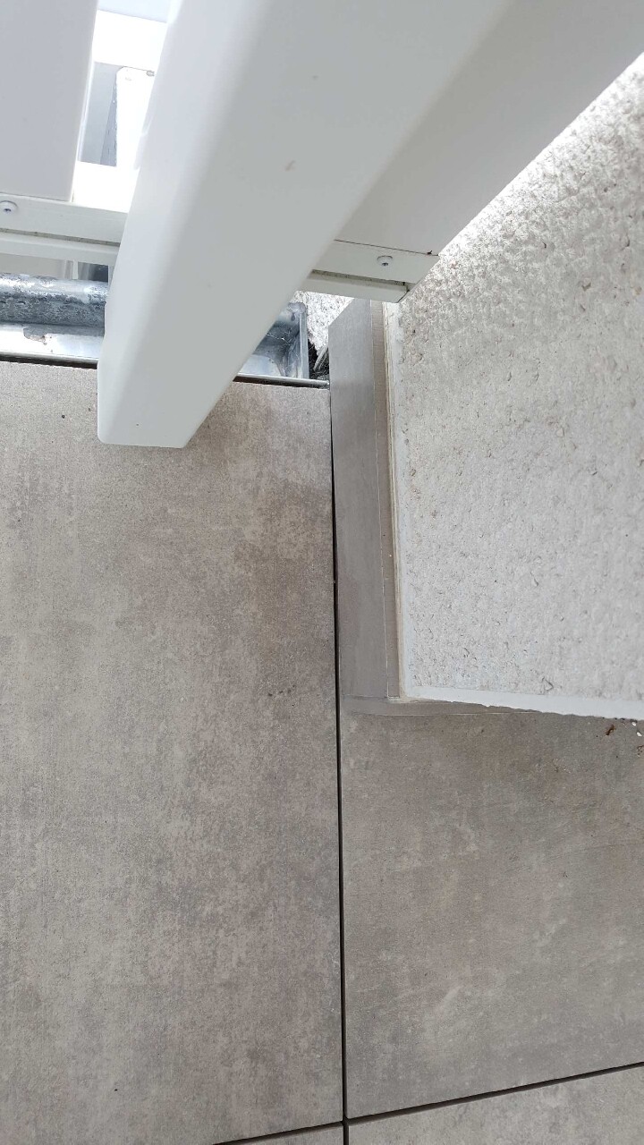 Terrassenboden mit großen Fliesen, Betonwand und weiße Metallunterkonstruktion