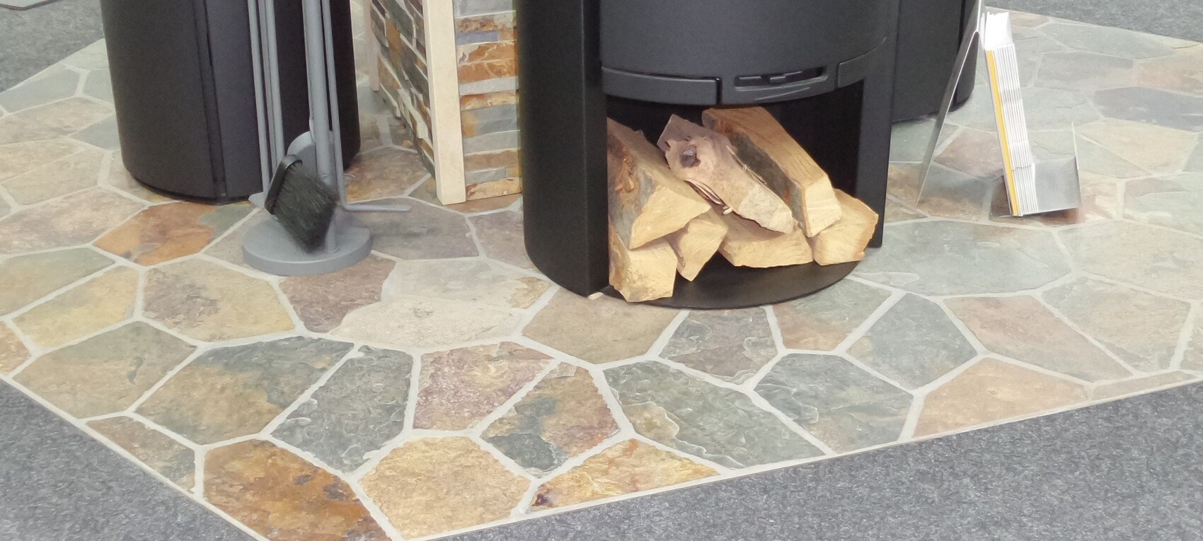 Außenbereich mit Steinplatten-Terrasse und Holzlager im Kaminofen.