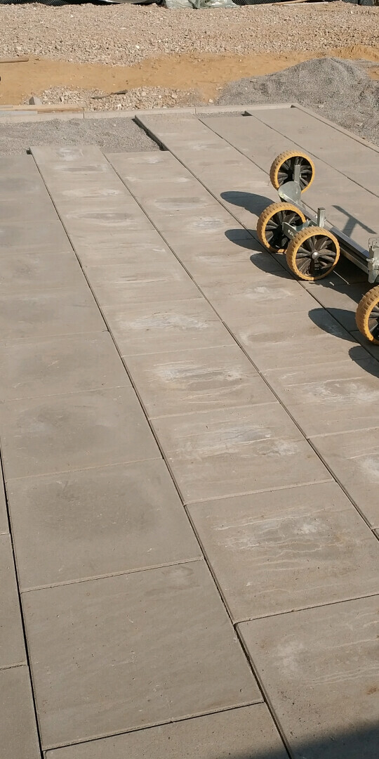 Außenbereich mit großen Terrassenplatten aus Beton, Bauplatz und Baugerät im Hintergrund