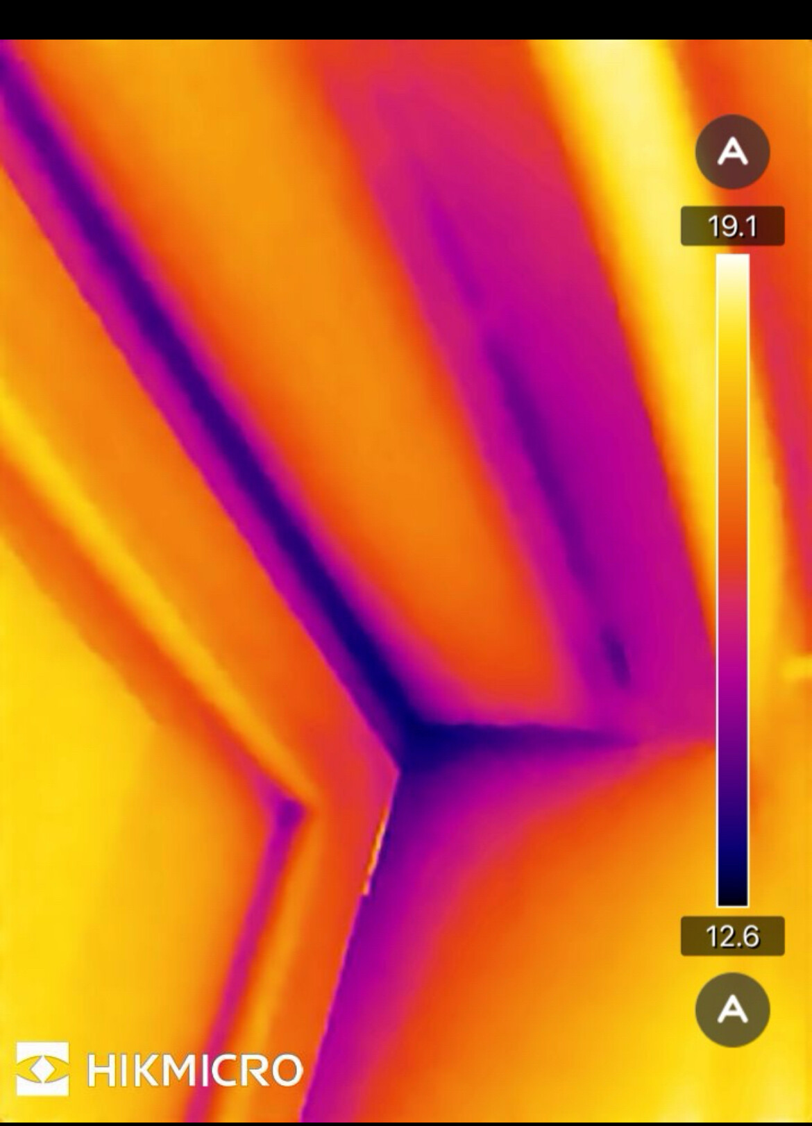 Wärmebild: Ecke mit gelb/orange Wärme und violetten Kühlzonen; Hikmicro-Logo unten.