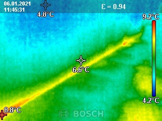 Thermografische Aufnahme eines Gebäudes mit Temperaturunterschieden und gelber Wärmeleitungslinie.
