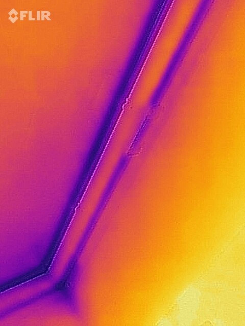 Thermografie einer Gebäudewand mit Dämmung, orange-lila Farbbereiche.