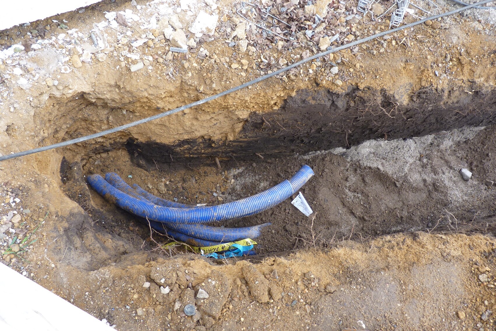 Baugrube im Fundamentbereich mit blauen flexiblen Rohren auf Baustelle