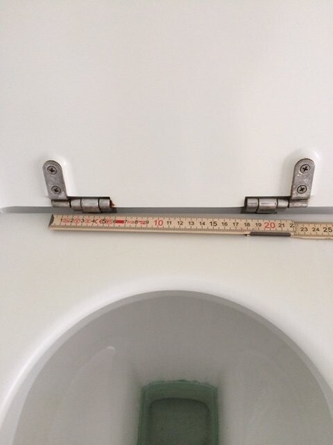 WC mit offenem Deckel und Maßband zur Messung im Badezimmer