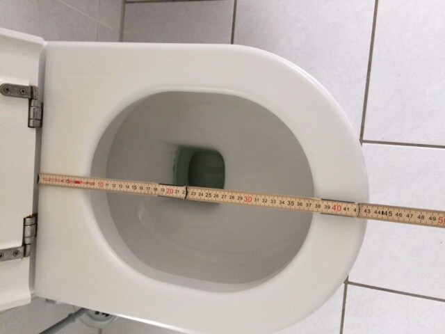 Weiße Toilette im Badezimmer mit Maßband