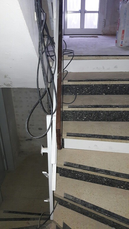 Innenbereich mit unfertiger Treppe, Kabelverlegung und Fenster im Hintergrund.