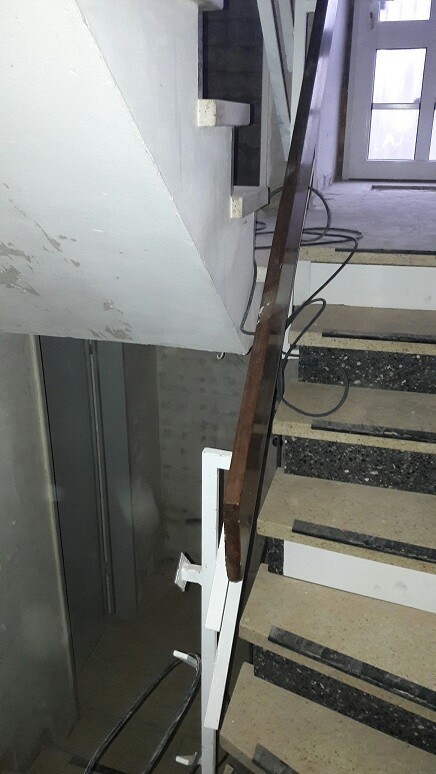 Unfertige Treppe in Bauabschnitt mit Metallgeländer und Kabeln.