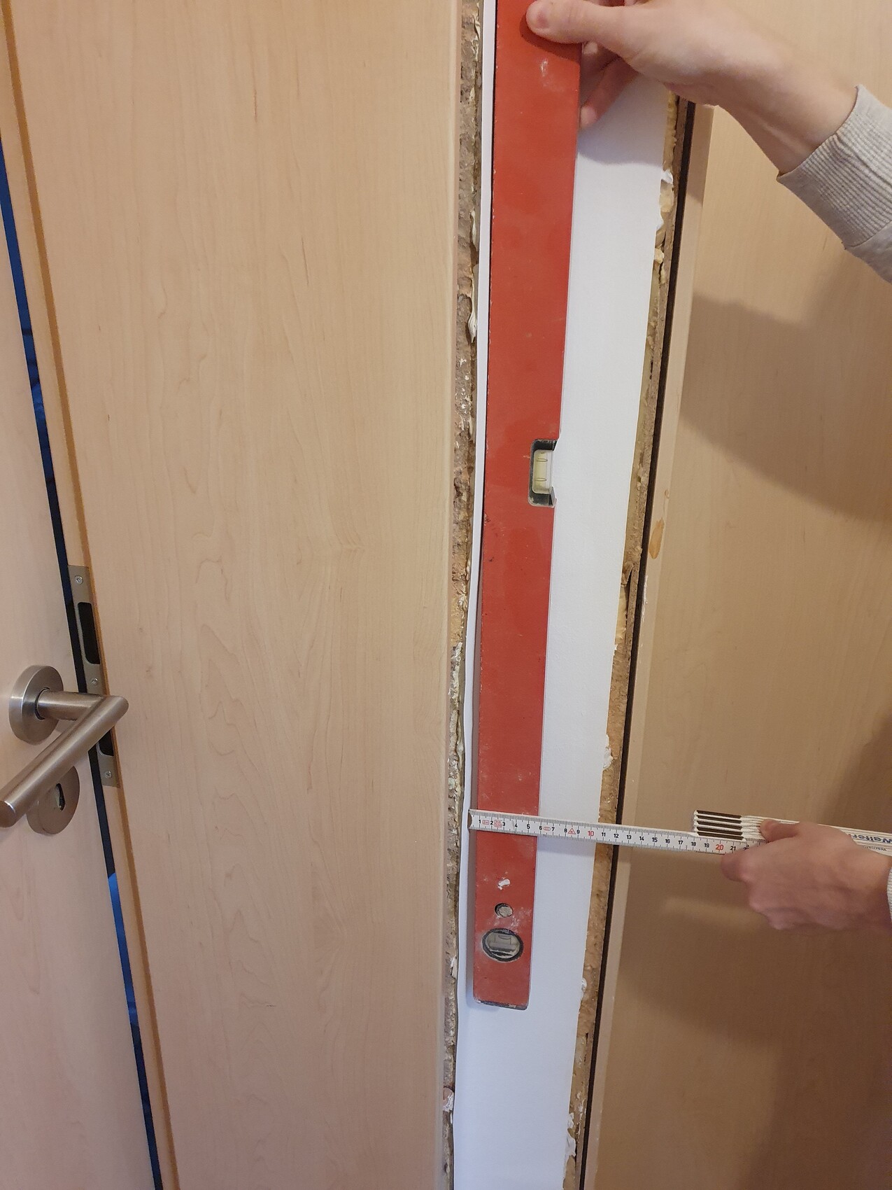 Hand misst Türrahmen mit Messband bei Innenausbauarbeiten