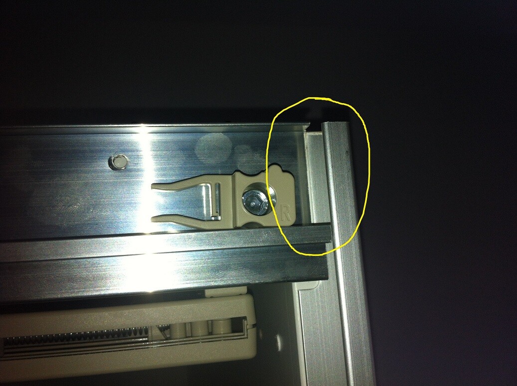 Nahaufnahme eines Metall-Schienenführungsprofils mit beige Kunststoffhalter und Schraube.