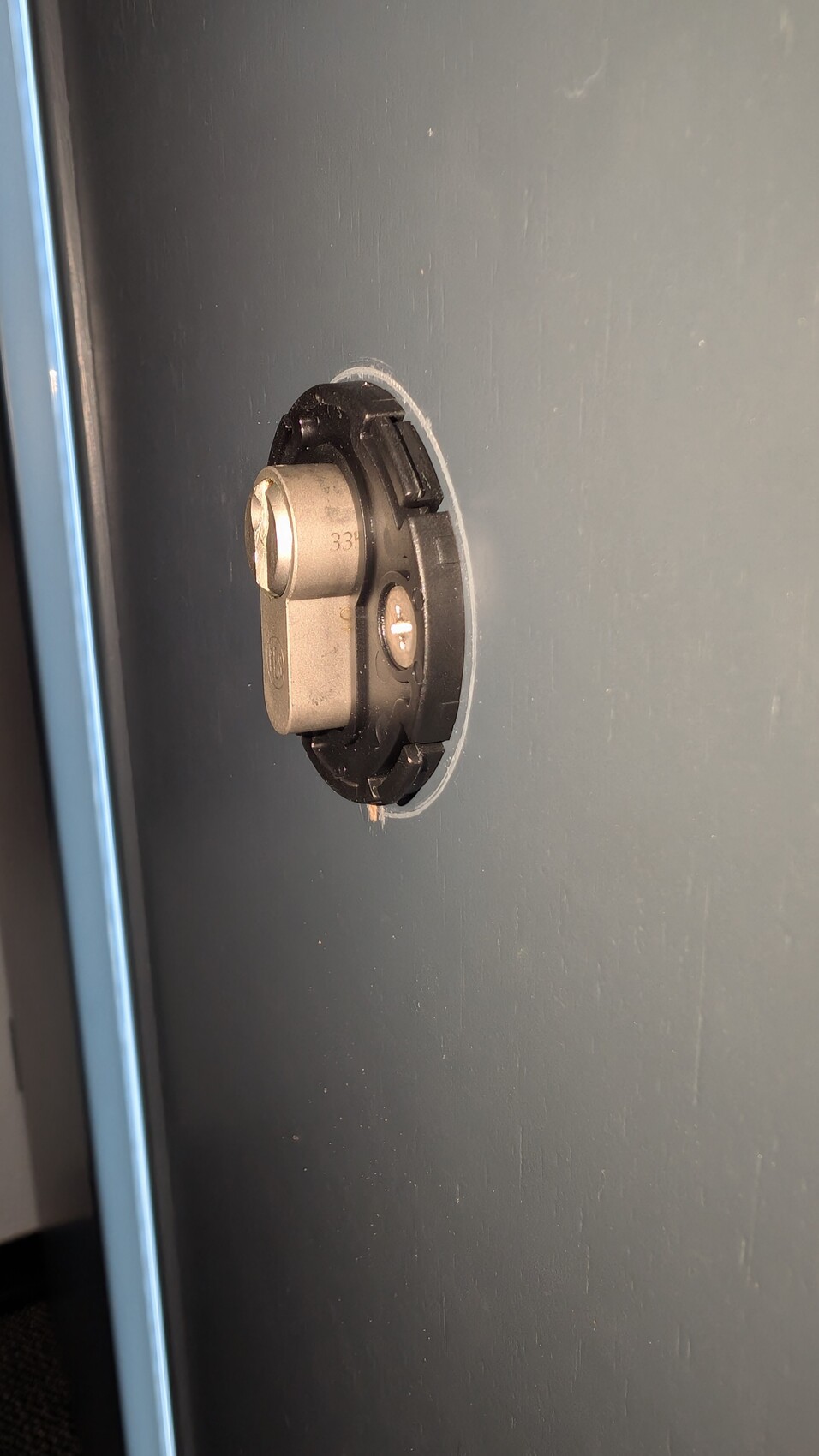 Nahaufnahme eines metallischen Türschloss-Zylinders in einer blauen Tür