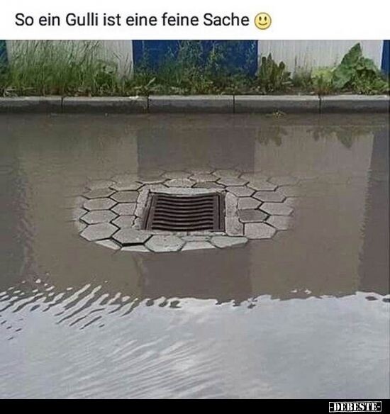 Überflutete Pflasterfläche mit Gulli-Rost in der Mitte, ringsum hexagonale Pflastersteine.