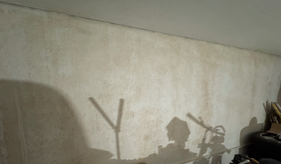 Unbearbeitete Kellerwand aus Beton mit Schatten von Gegenständen im Lagerraum