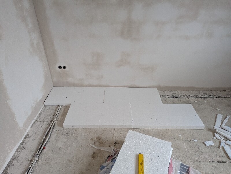 Bauzimmer mit weißen Styroporplatten auf dem Boden und Kabelresten.