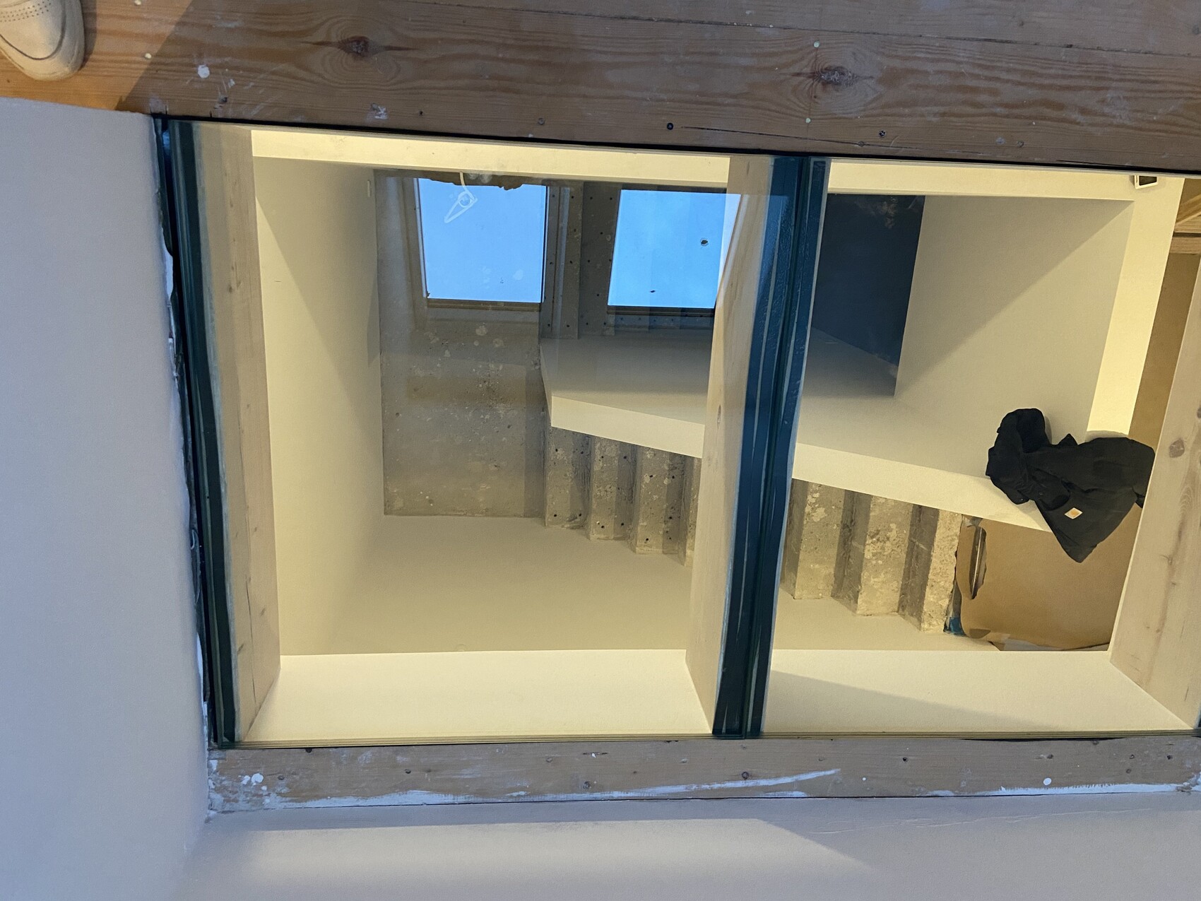 Innenraum einer Baustelle mit Betontreppe, weißen Wänden und Jacke auf einem Karton.