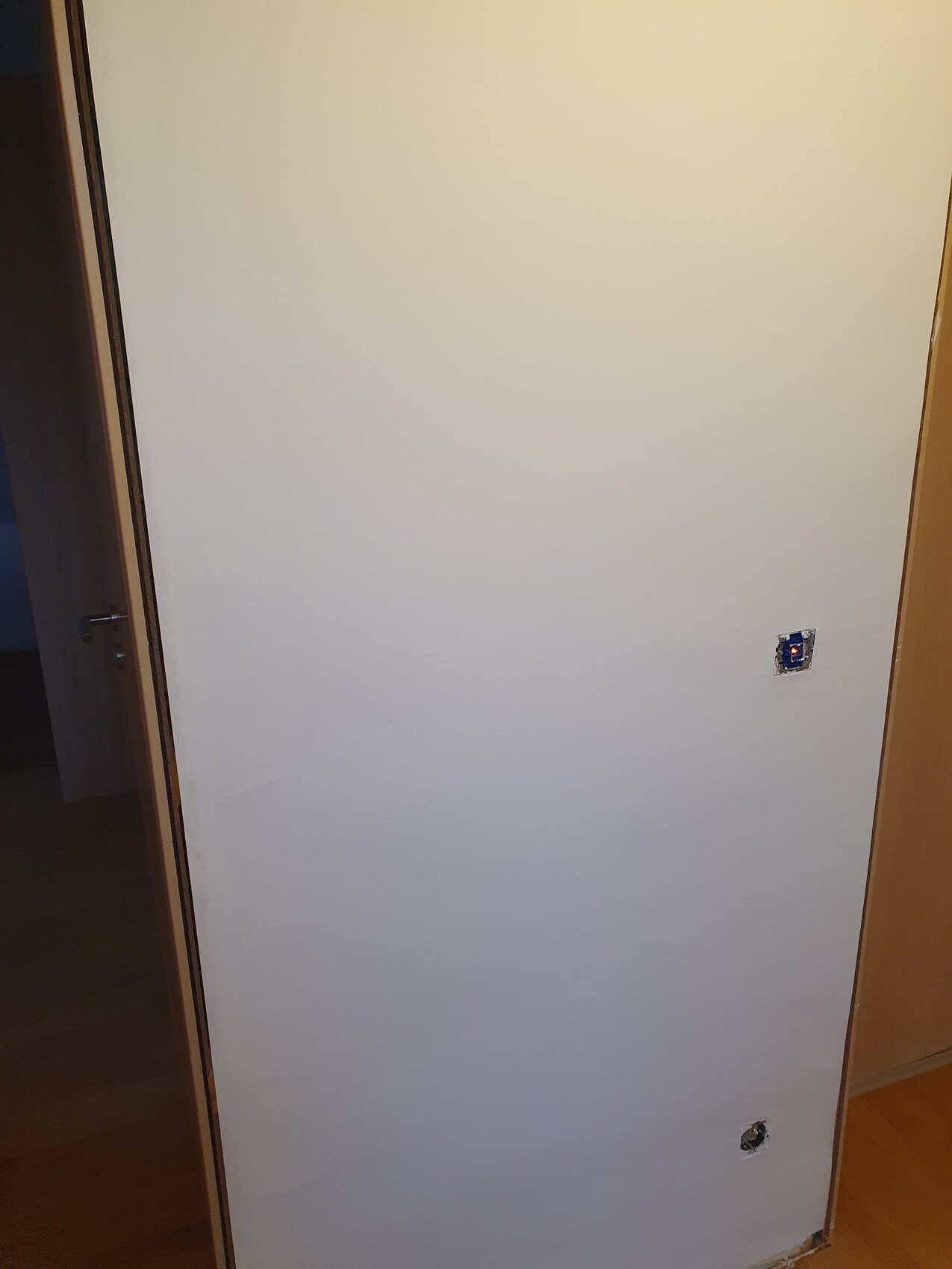 Weiße Innenwand mit ausgeschnittenen Wanddosen und sichtbaren Installationsöffnungen